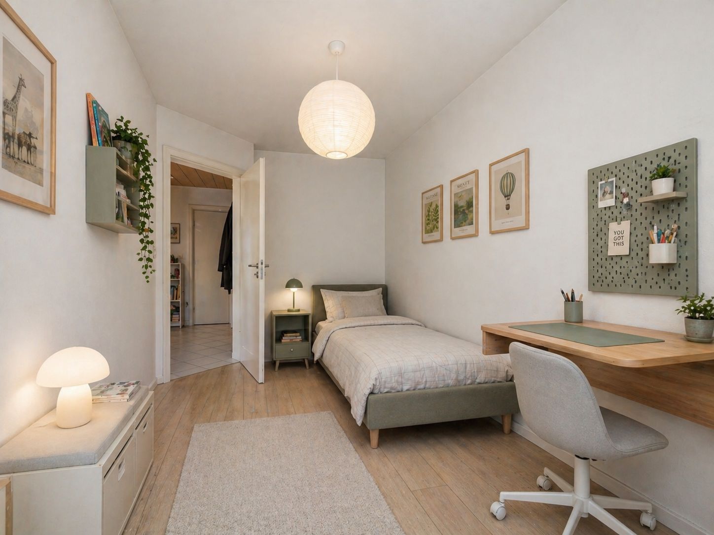 Helles Schlafzimmer mit Einzelbett, Schreibtisch, Stuhl und Bildern an der Wand.