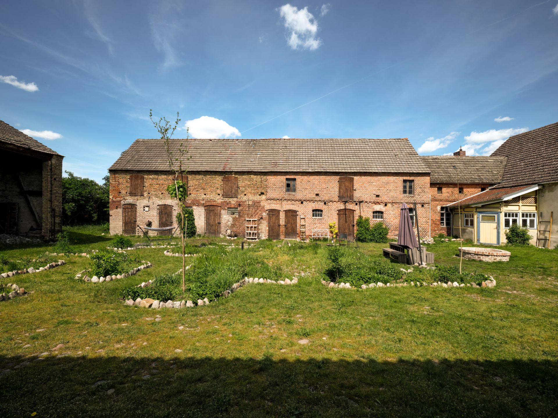 Backsteinhaus mit geschlossenem Fensterladen und großem Garten im Vordergrund.