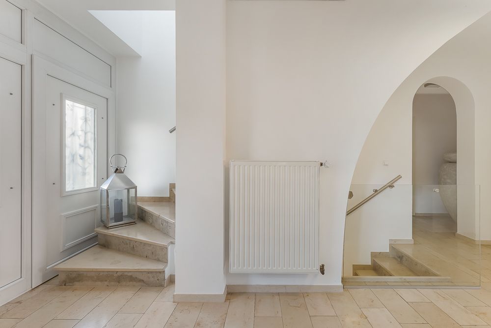 Heller Flur mit Treppe, Heizkörper und großer Laterne neben einer Tür.