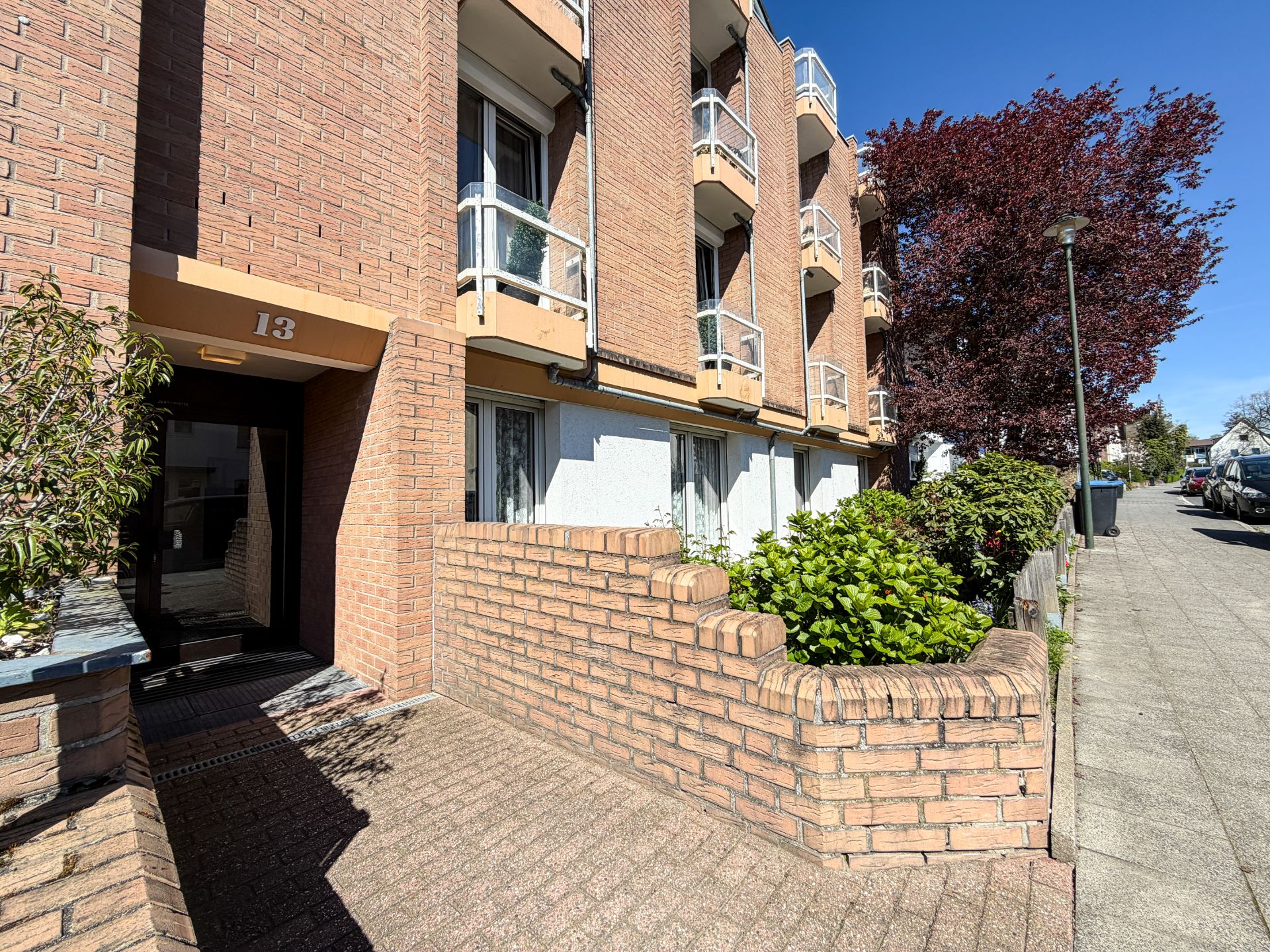 Eingang eines Mehrfamilienhauses mit Backsteinfassade und kleinen Balkonen.
