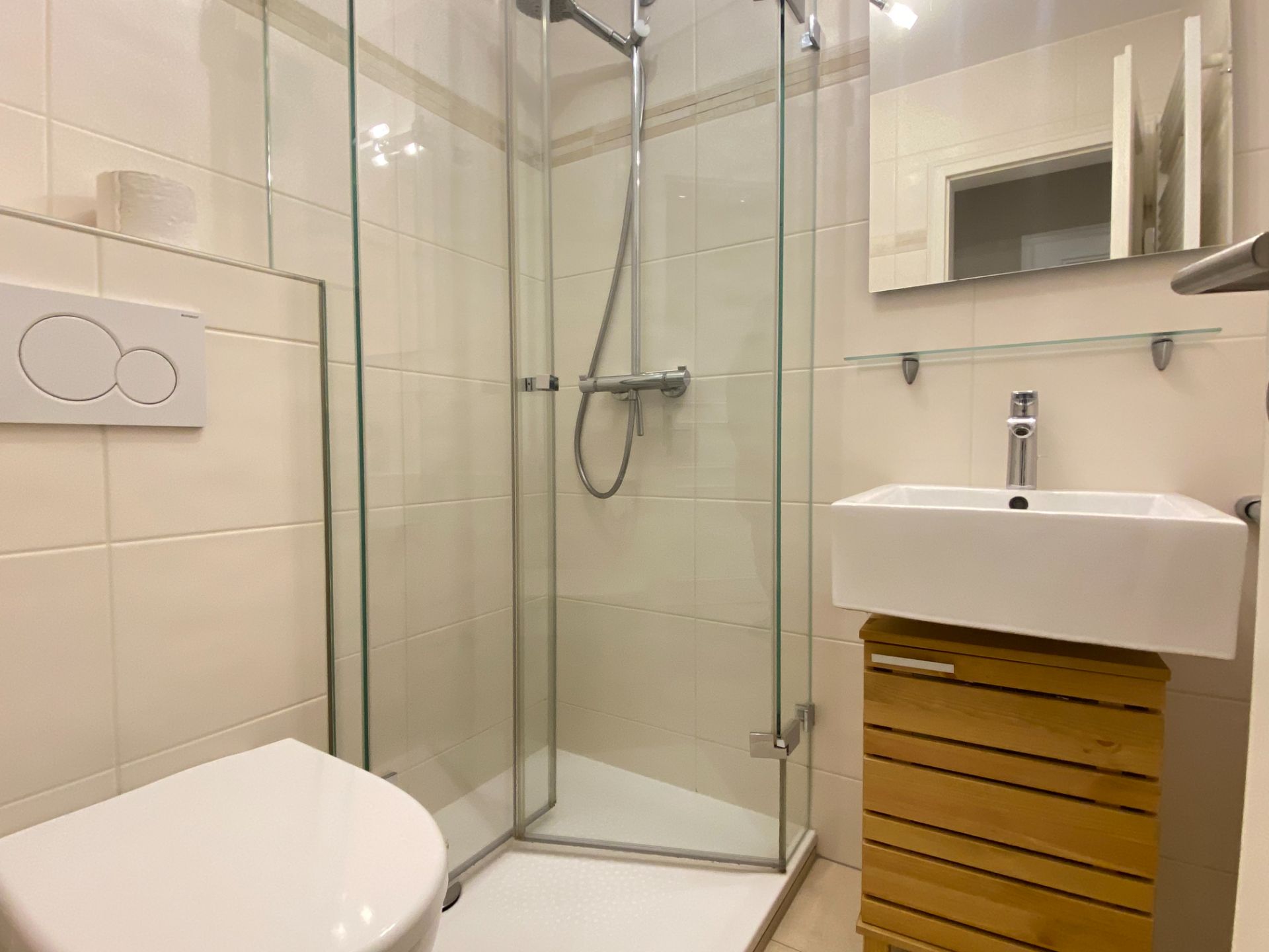 Modernes Bad mit Dusche, WC, Waschbecken und Spiegel.
