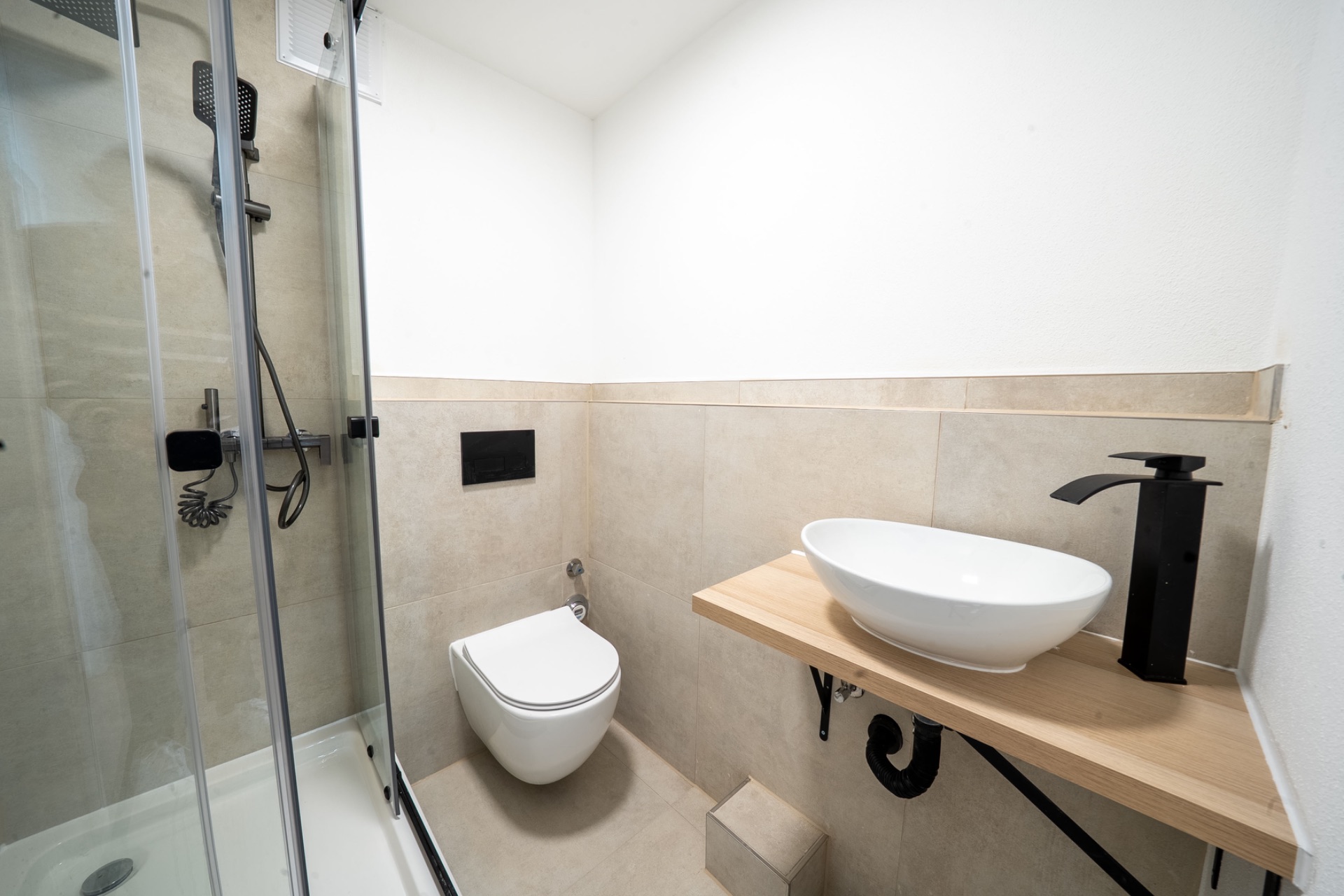 Modernes Badezimmer mit Dusche, Wandtoilette und Waschbecken auf Holztisch.