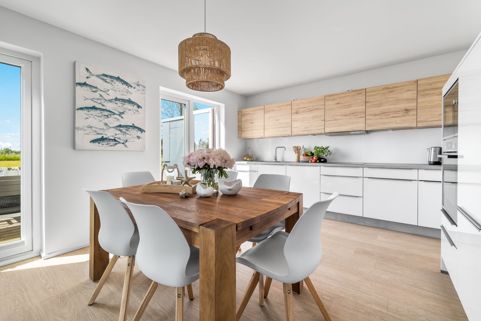 Helle Küche mit Holztisch, weißen Stühlen und modernen Holzschränken.