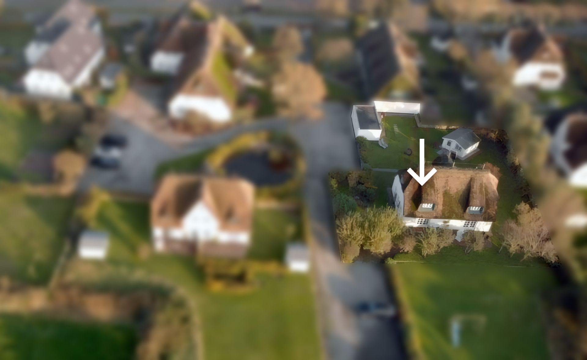 Luftaufnahme eines Hauses mit Garten; ein Pfeil zeigt auf das Dach des Hauses.