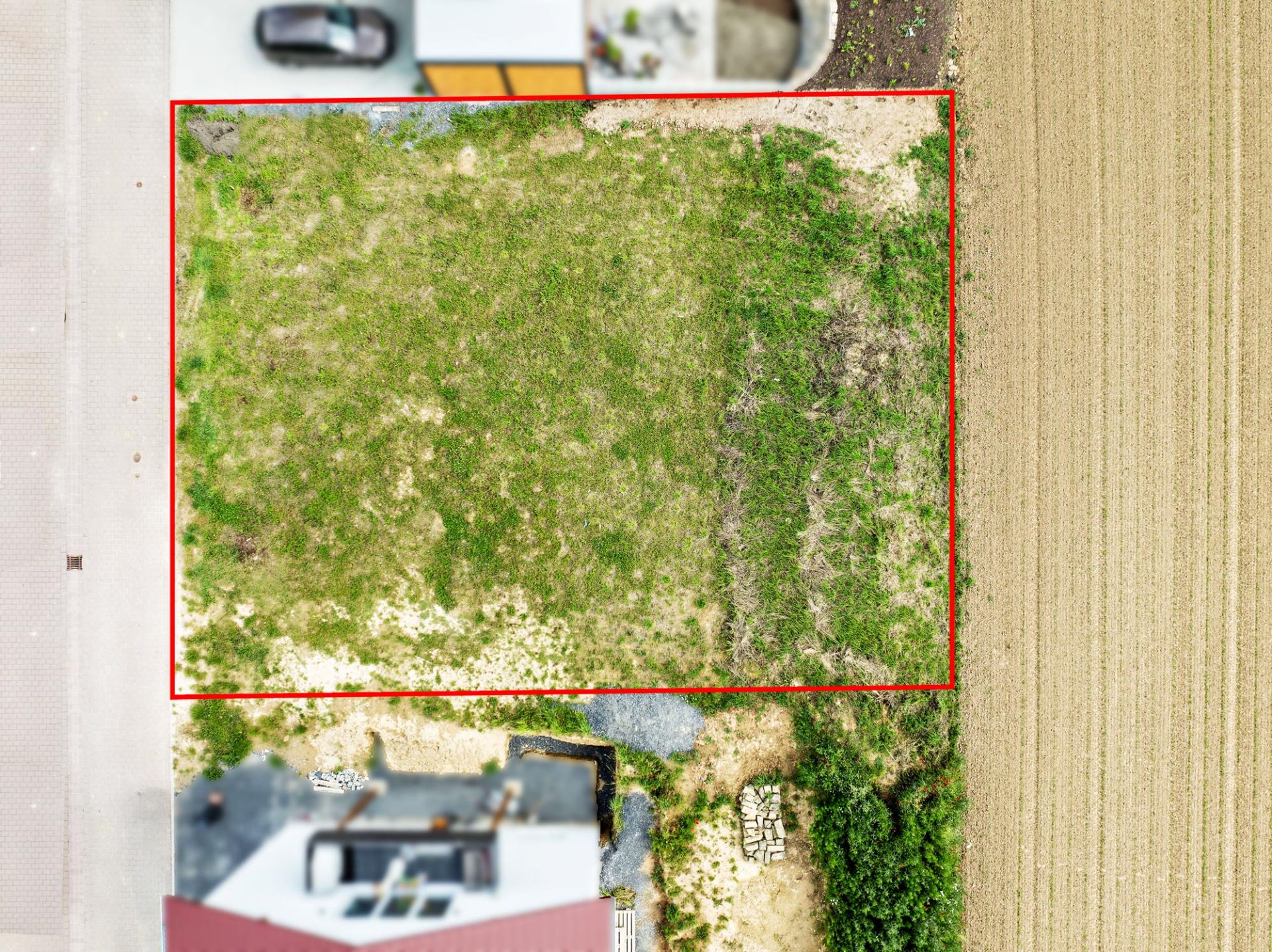 Luftaufnahme eines rechteckigen, grasbewachsenen Grundstücks mit rotem Rand.
