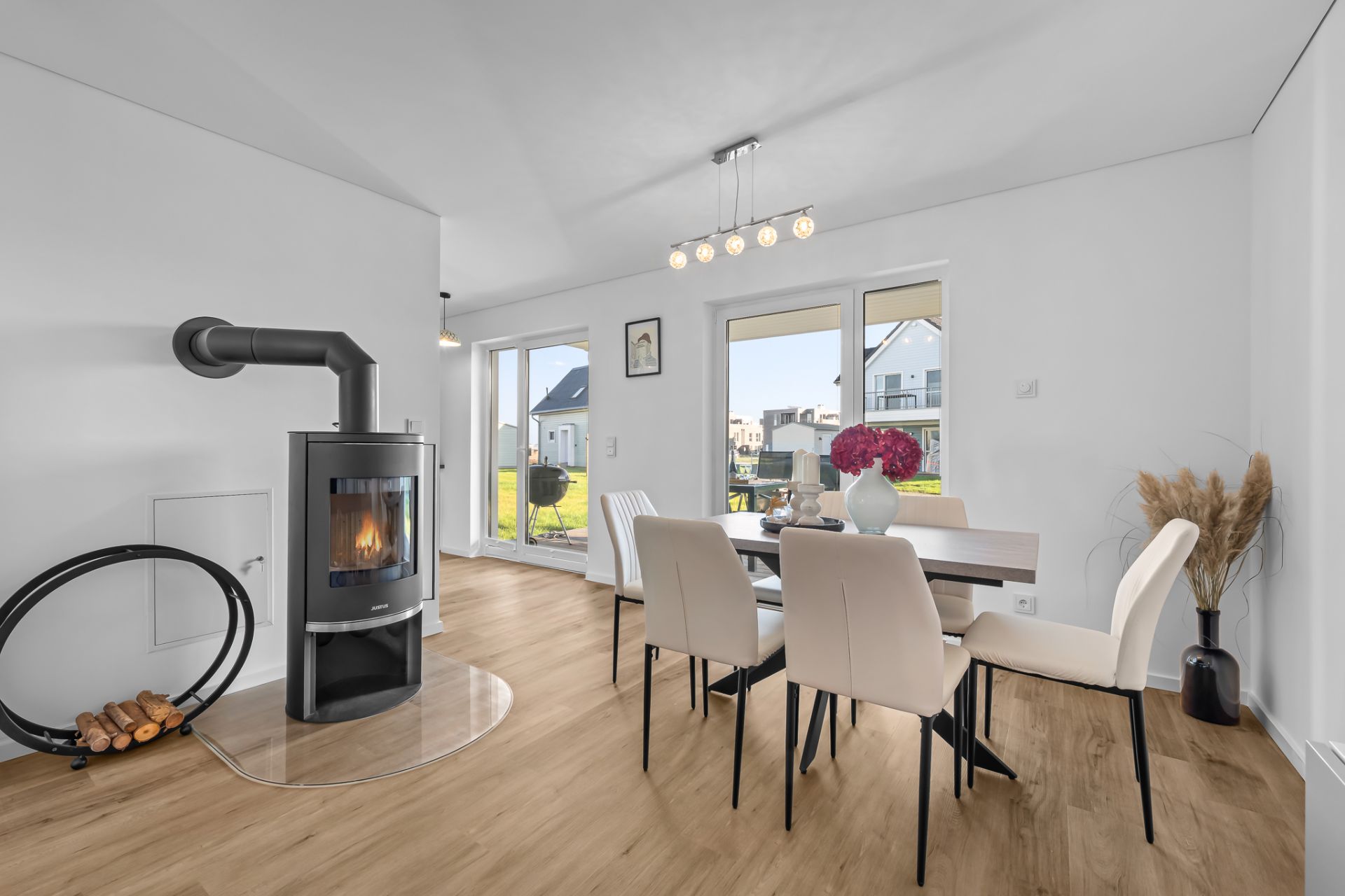 Helles Esszimmer mit Holzboden, Esstisch, Kaminofen und Blick in den Garten.
