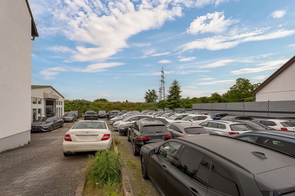 Mehrere Autos stehen dicht an dicht auf einem Parkplatz neben Wohngebäuden.