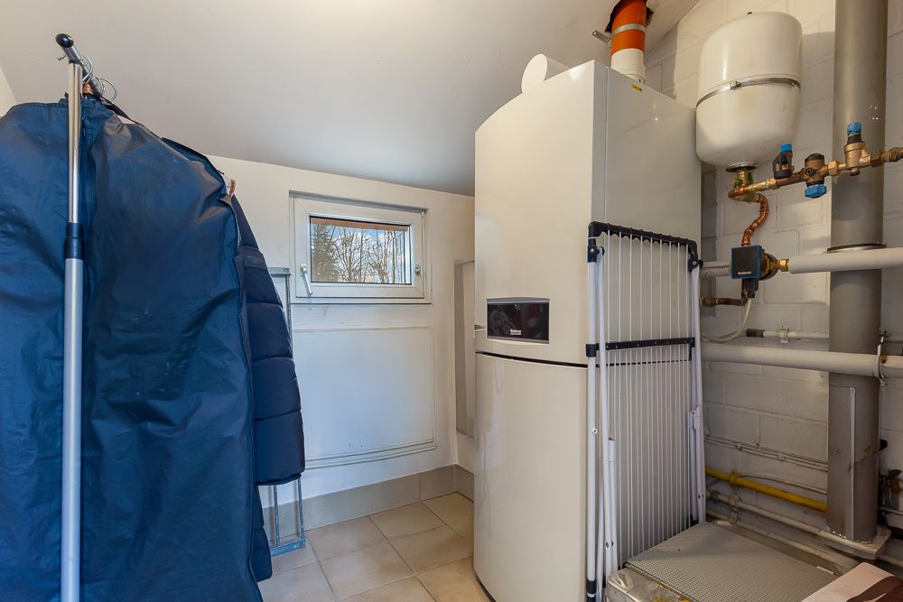 Hauswirtschaftsraum mit Heizungsanlage, Rohren und Fenster, daneben ein Kleiderständer.