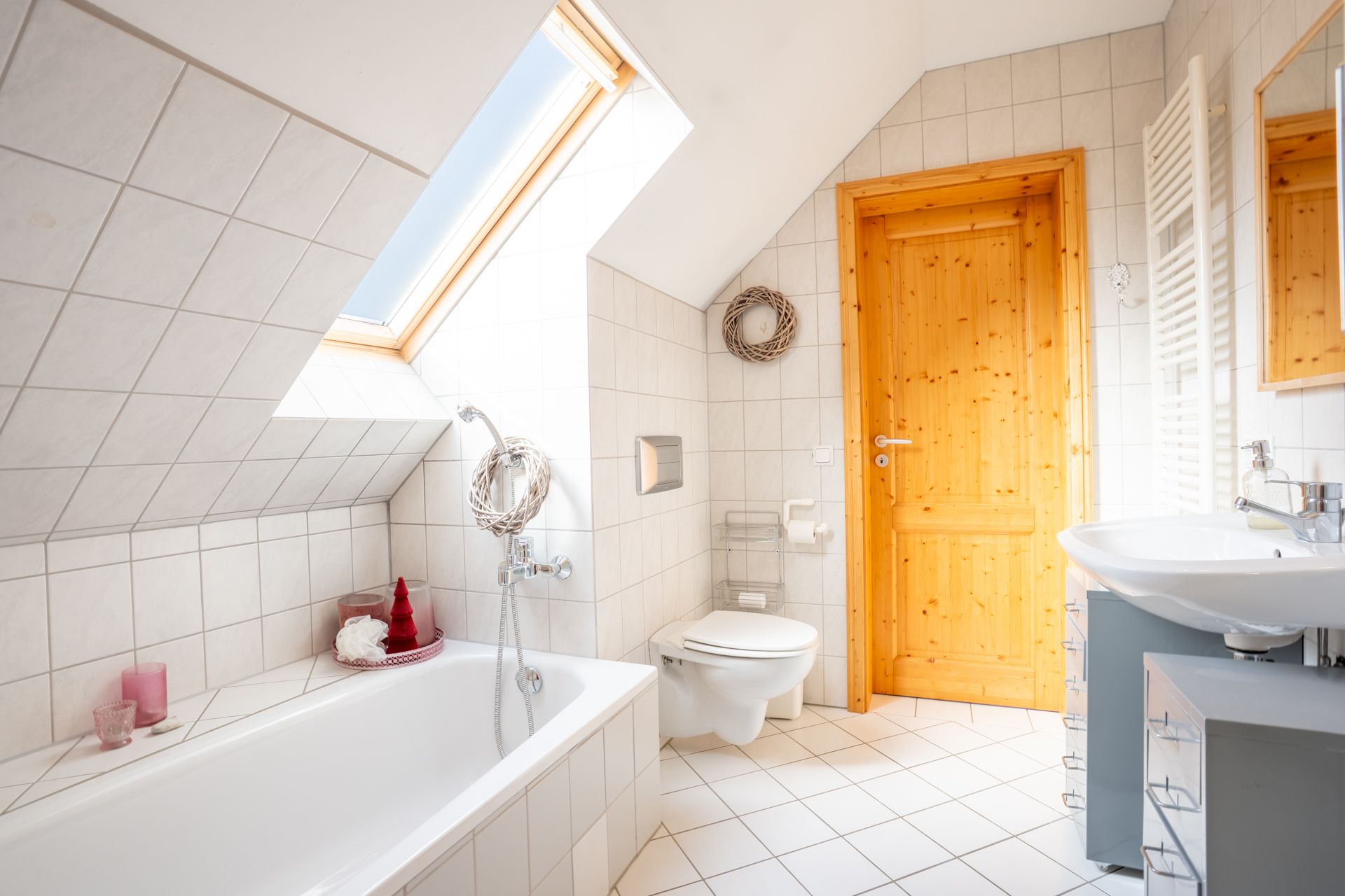 Helles Badezimmer mit Badewanne, WC, Waschbecken und Dachfenster.