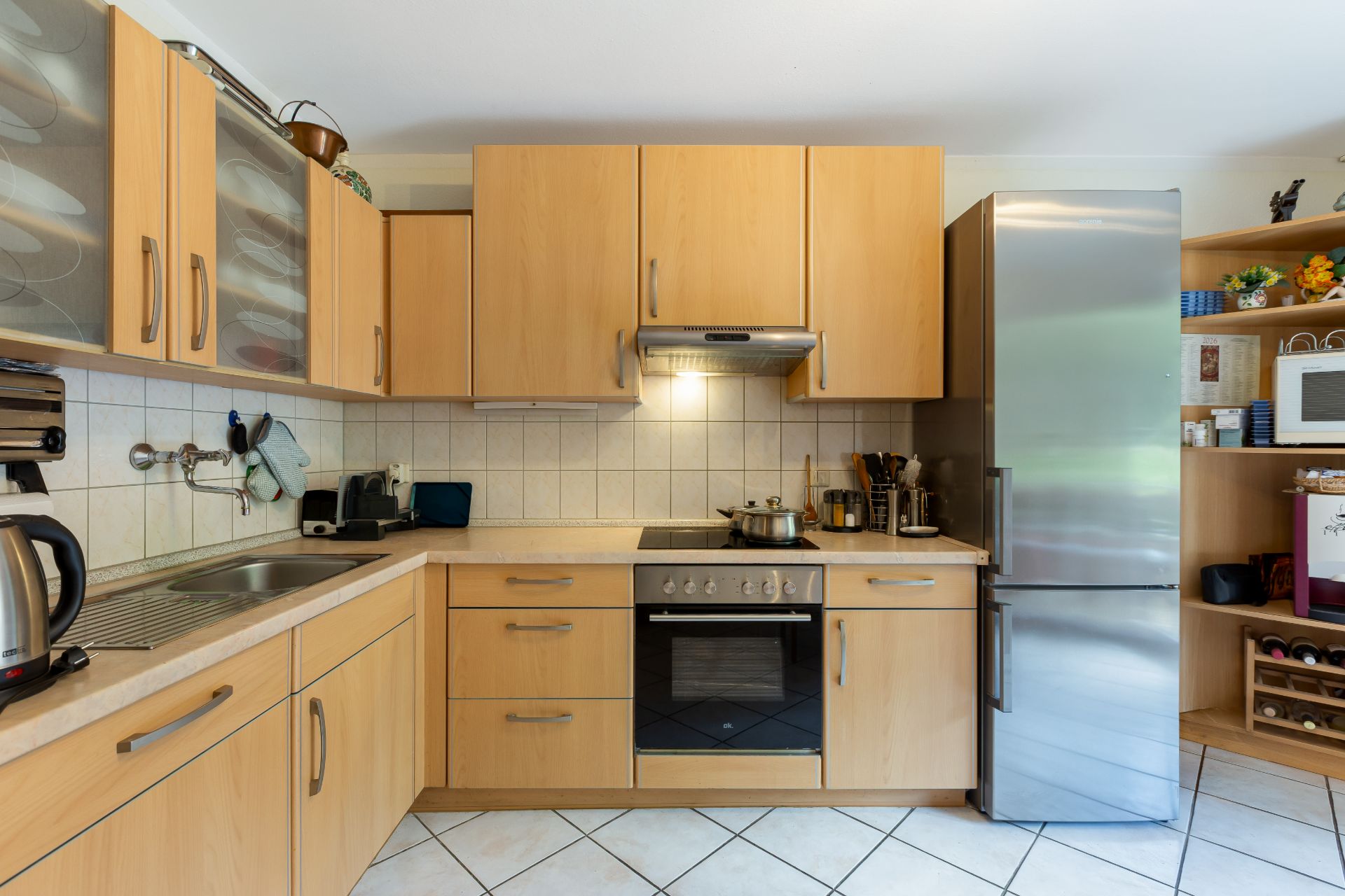 Moderne Küche mit Holzschränken, Edelstahlherd und großem Kühlschrank.