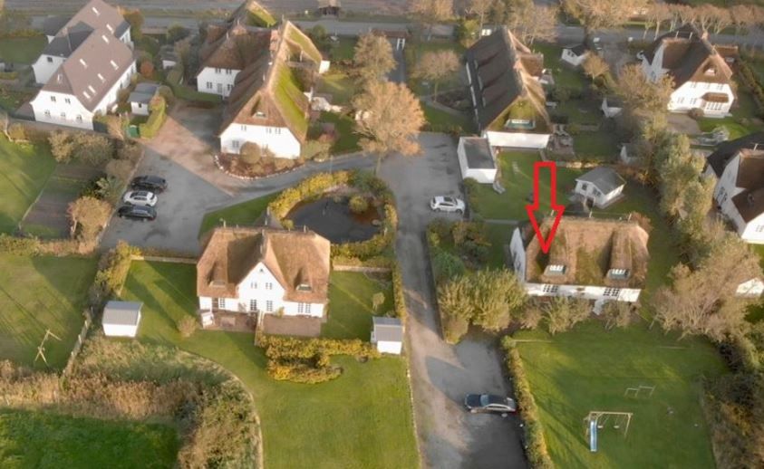 Luftaufnahme mehrerer Einfamilienhäuser mit Gärten, ein Haus ist mit einem roten Pfeil markiert.