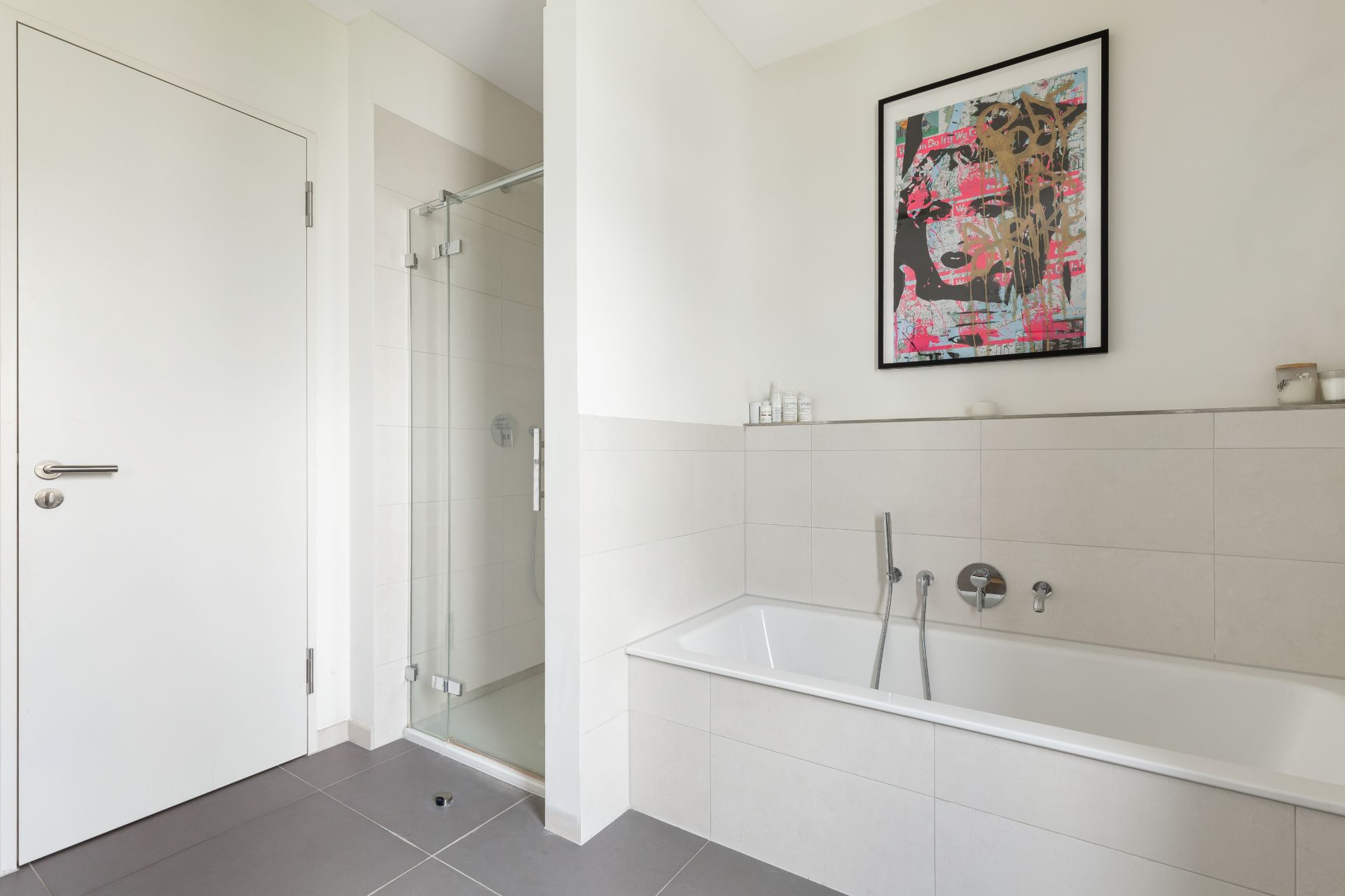 Modernes Badezimmer mit Badewanne, Dusche und einem bunten Bild an der Wand.