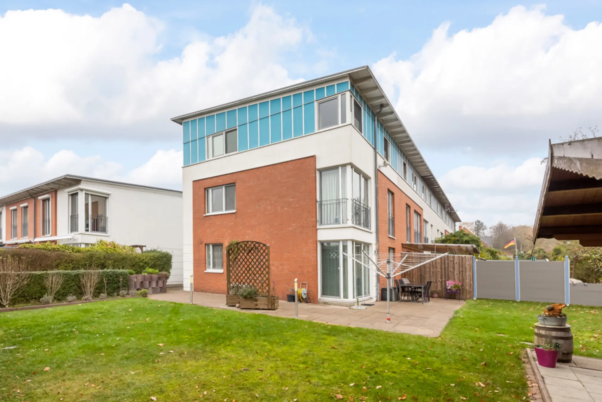 Modernes Wohngebäude mit Garten, Terrasse und Wäscheständer im Vordergrund.