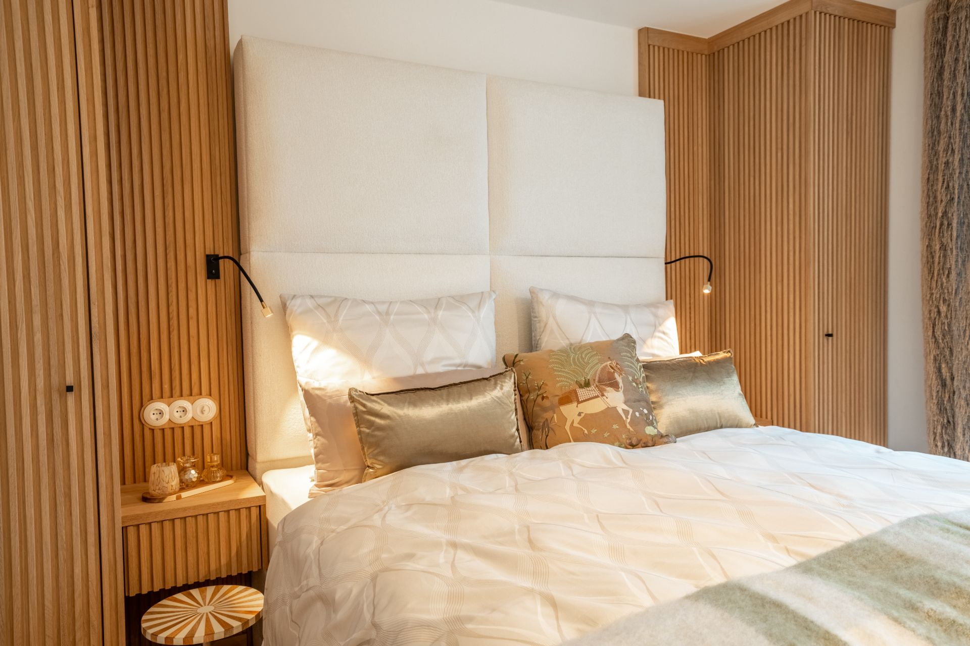 Modernes Schlafzimmer mit großem Bett, Holzmöbeln und dekorativen Kissen.