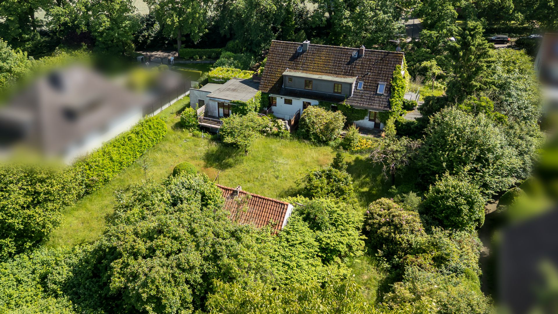 Luftaufnahme eines Hauses mit großem Garten und vielen Bäumen.