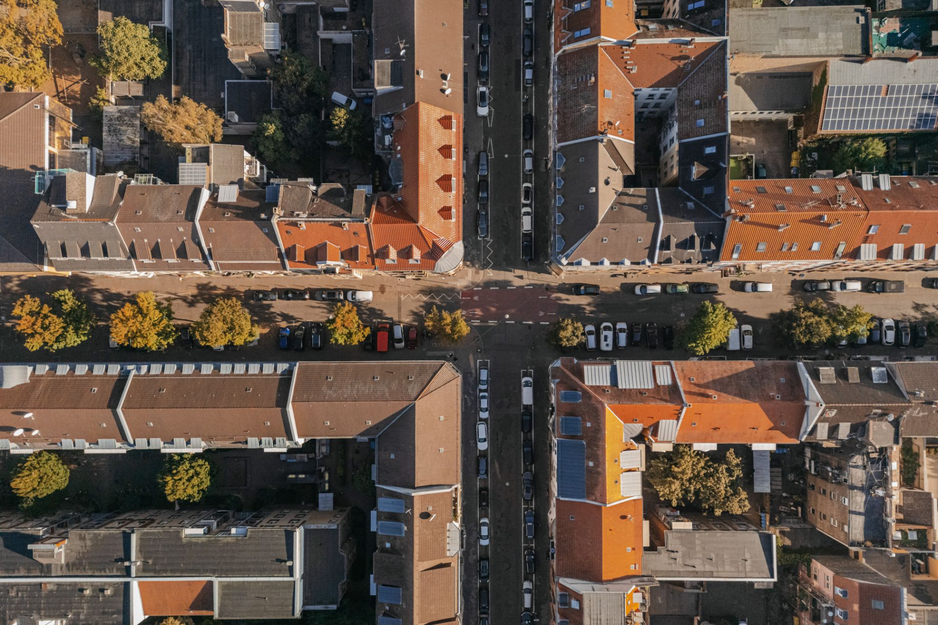 Luftaufnahme eines Wohnviertels mit roten Dächern und Straßen mit parkenden Autos.