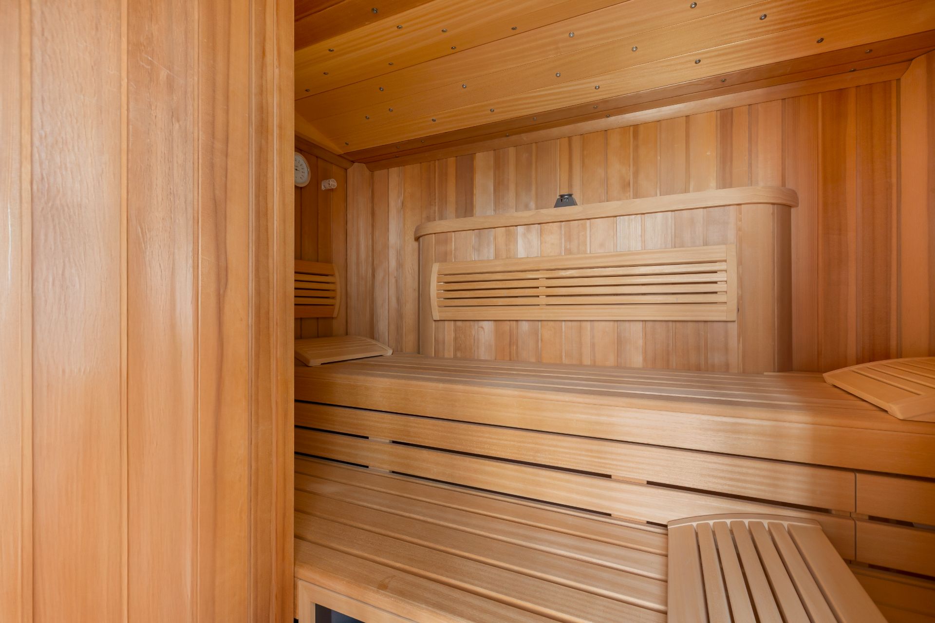 Innenansicht einer modernen Holzsauna mit Bänken und Seitenteilen aus Holz.