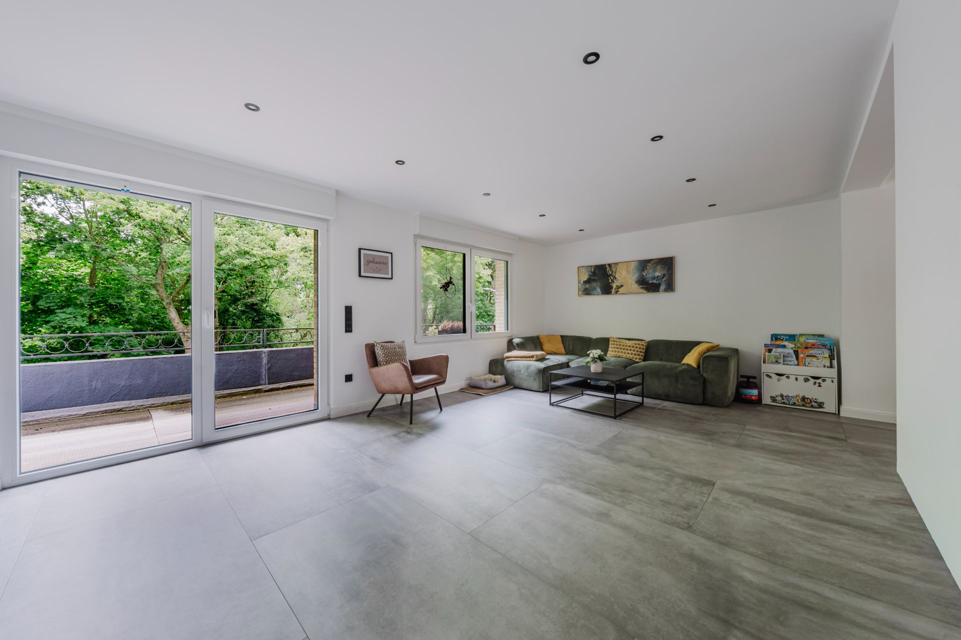 Helles Wohnzimmer mit großer Eckcouch, Sessel, Couchtisch und Zugang zu einem Balkon.