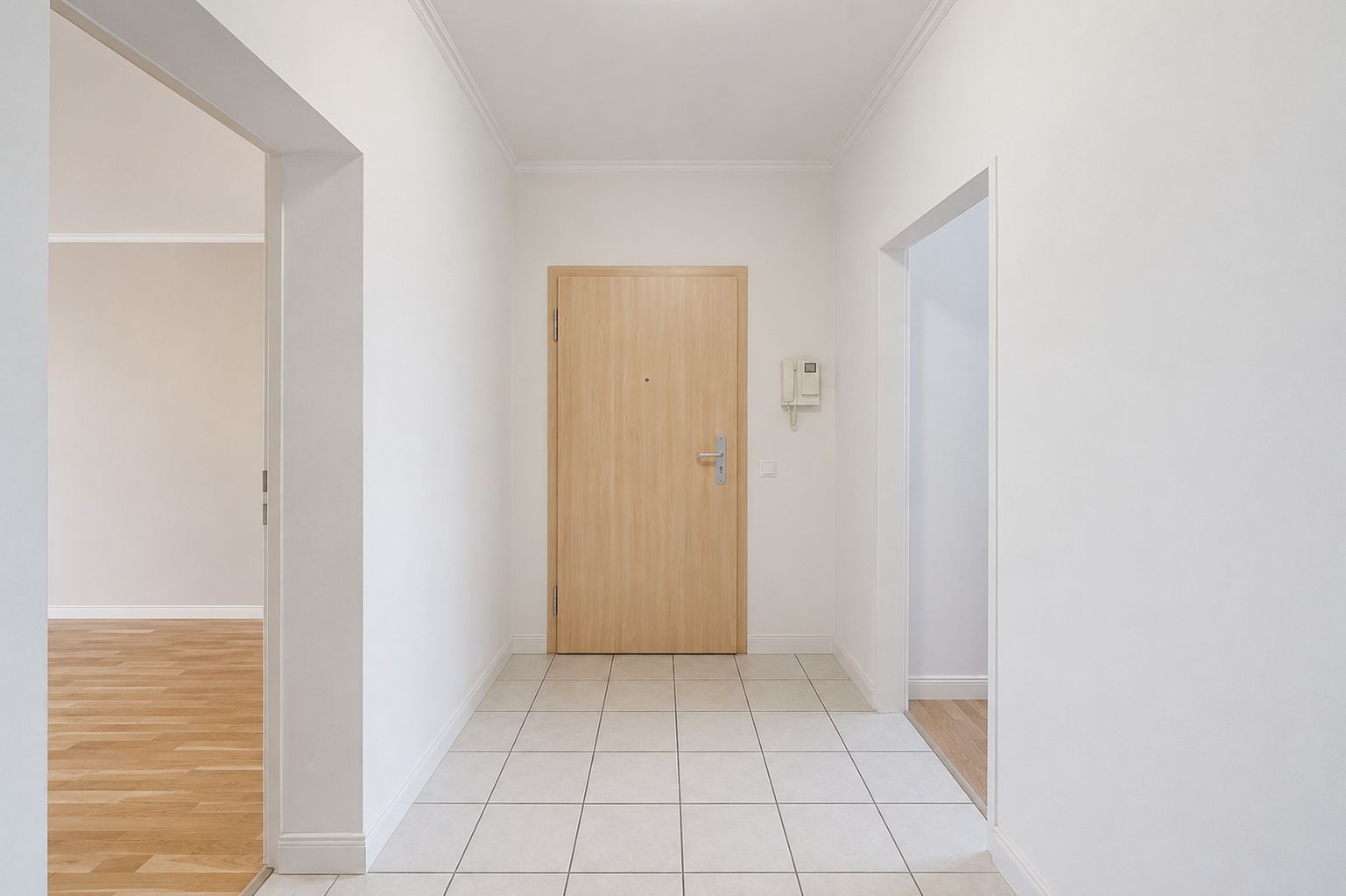 Heller Flur mit weiß gestrichenen Wänden, Fliesenboden und Holztür.