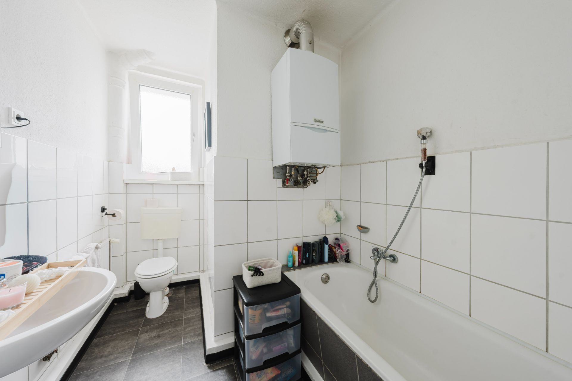 Helles Badezimmer mit Badewanne, Waschbecken, Toilette und weiß gefliesten Wänden.