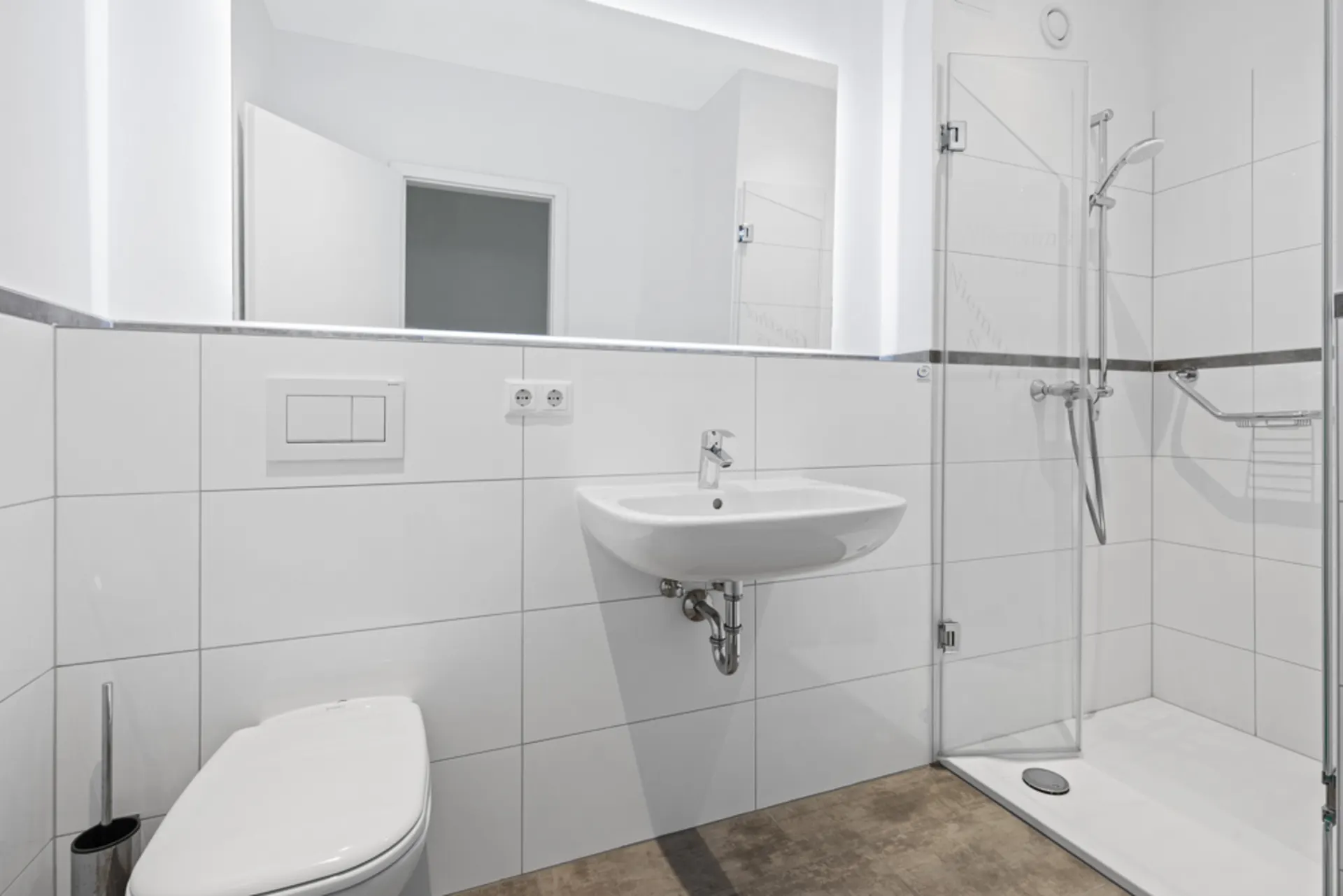 Modernes, weiß gefliestes Badezimmer mit WC, Waschbecken und offener Dusche.
