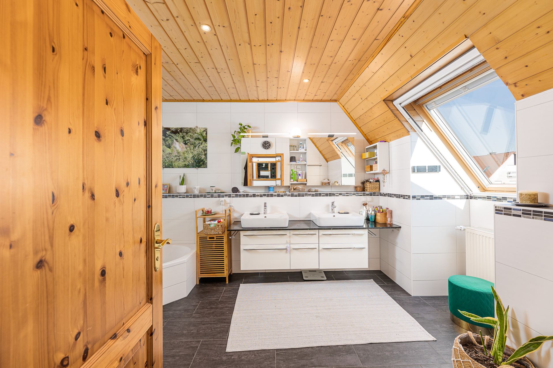 Modernes Badezimmer mit Holzdecke, zwei Waschbecken, großem Spiegel und Dachfenster.