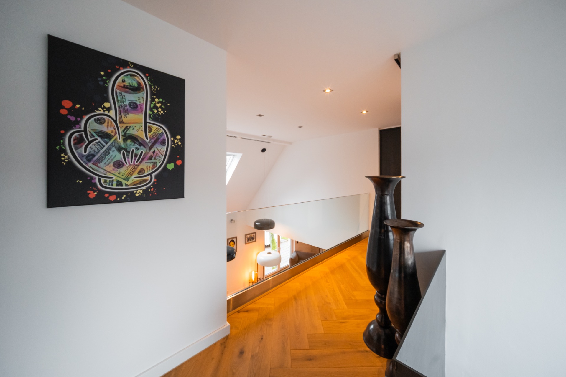 Heller Flur mit Holzfußboden, zwei großen Vasen und bunt bemalter Wandkunst.