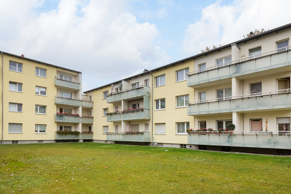 Mehrfamilienhaus mit mehreren Balkonen und grünem Innenhof.