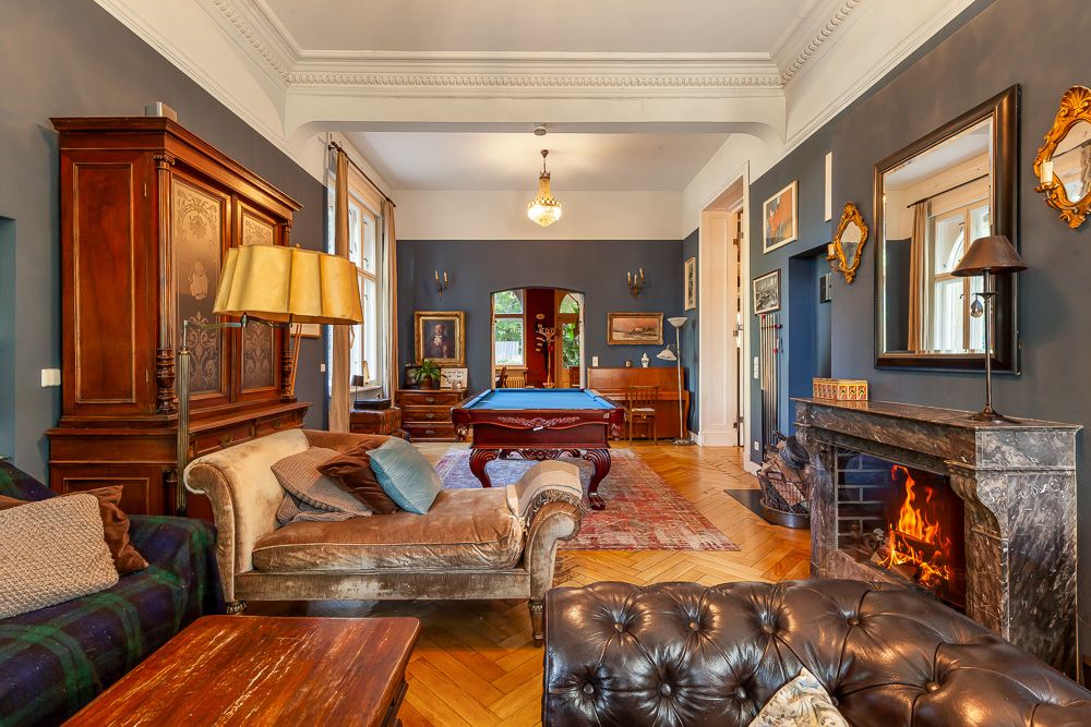 Elegantes Wohnzimmer mit Kamin, Billardtisch, antiken Möbeln und blauen Wänden.