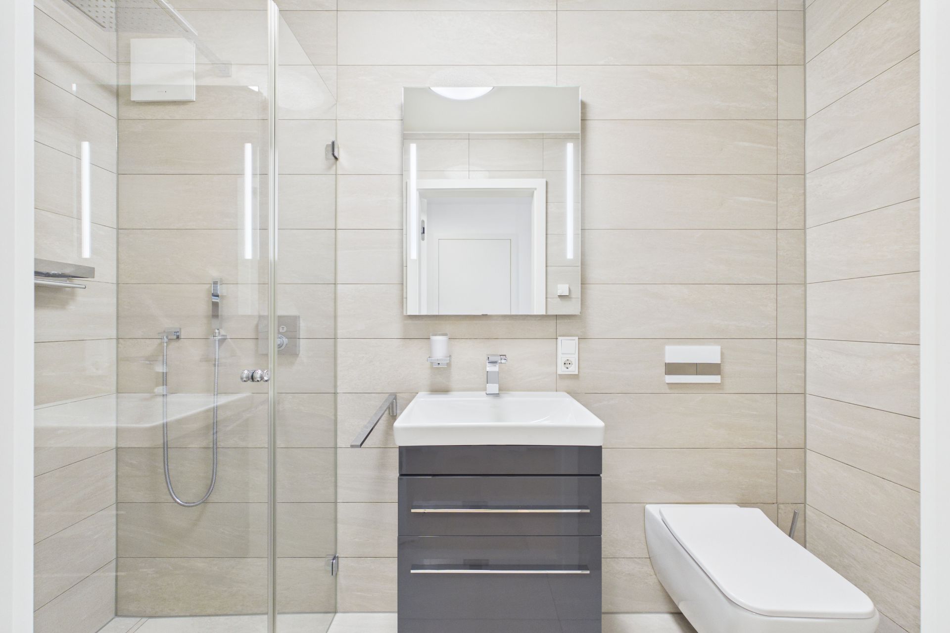 Modernes Badezimmer mit Dusche, Waschbecken, Spiegel und Wandtoilette.