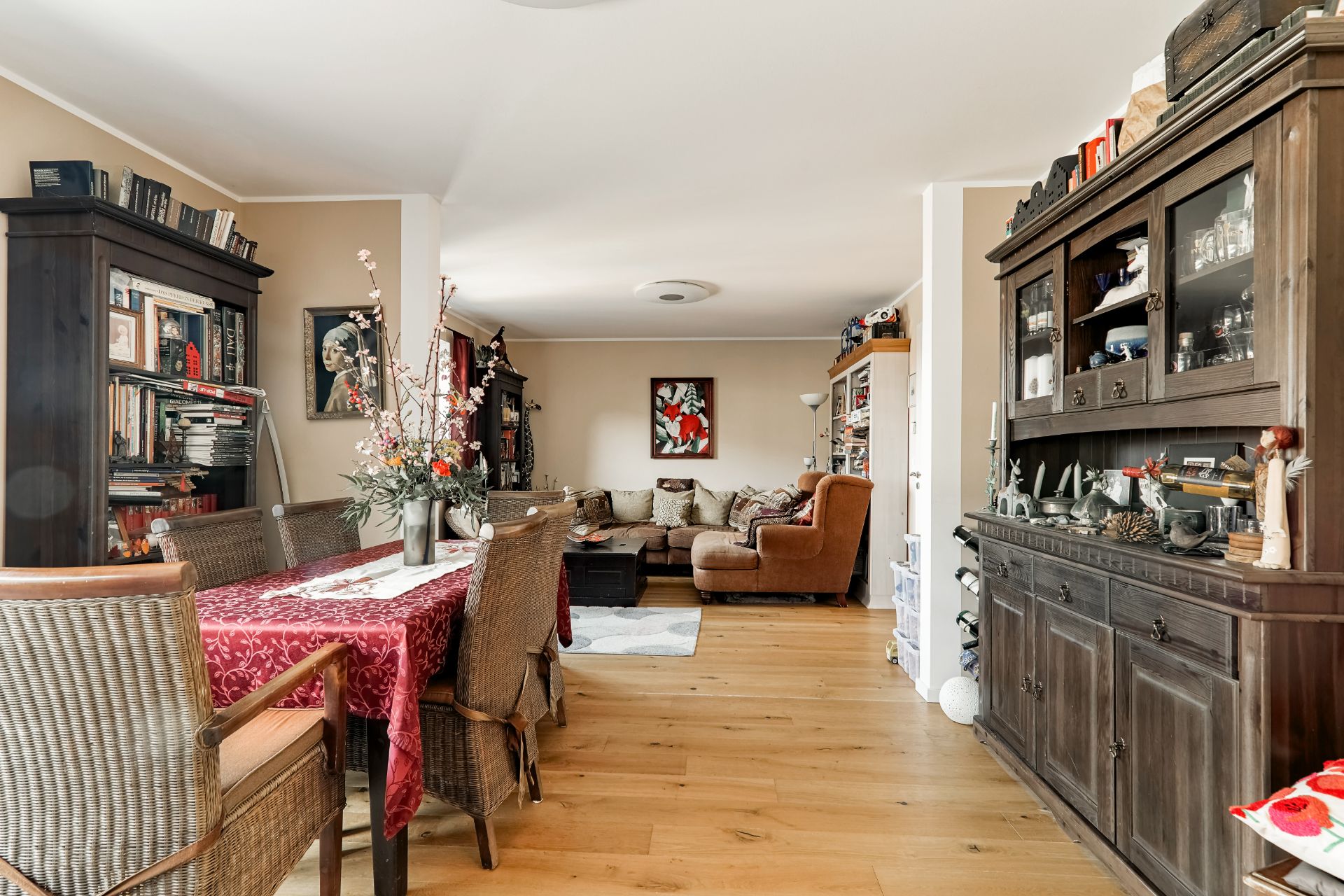 Wohnzimmer mit Holzmöbeln, Esstisch, Stühlen, Sofa und Regalen auf Holzfußboden.