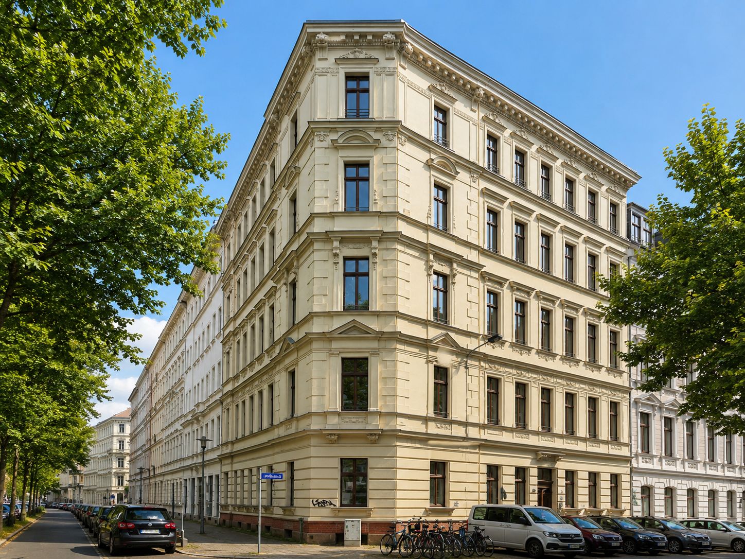 Eckiges, vierstöckiges Wohnhaus mit hellem Fassadenputz und großen Fenstern an einer ruhigen Straße.