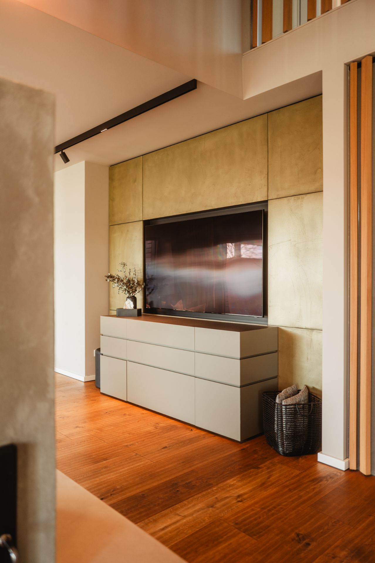 Modernes Wohnzimmer mit Fernseher, Kommode und Dekokorb auf Holzfußboden.