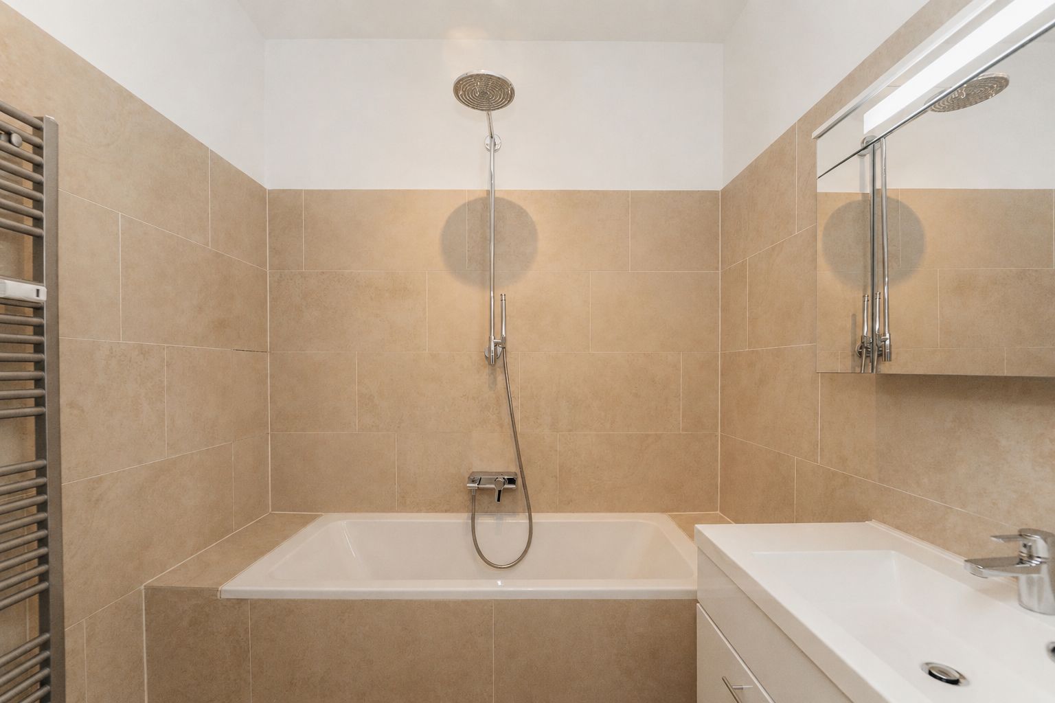 Modernes Badezimmer mit Badewanne, Dusche, Waschbecken und Spiegel.