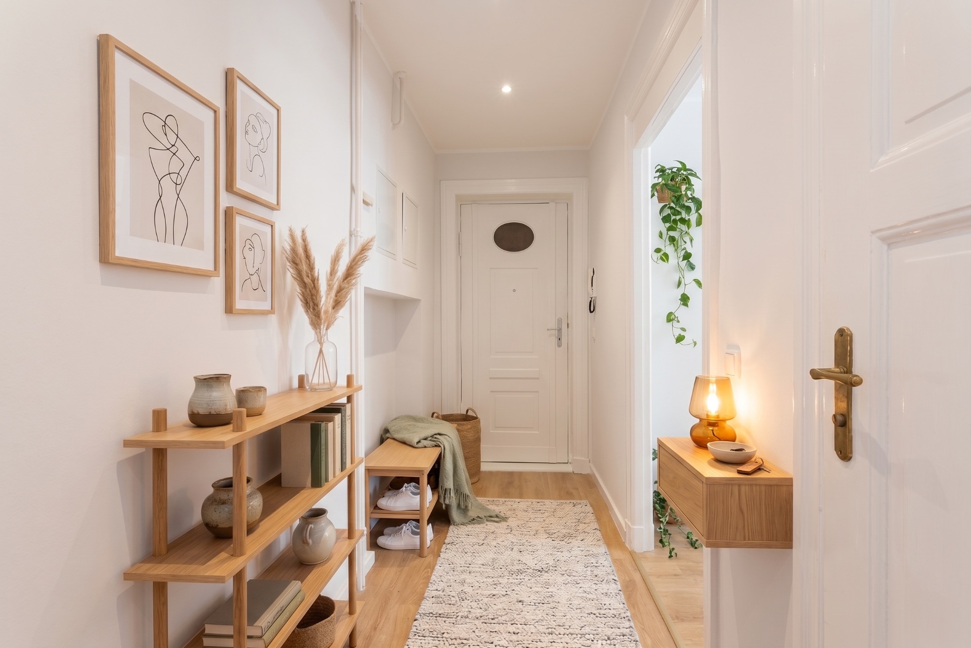 Heller Flur mit Holzregal, Bildern an der Wand, Teppich und Dekorationen.