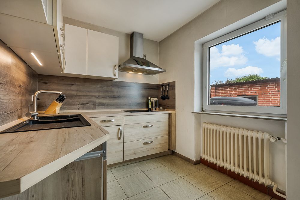 Moderne Küche mit Holzarbeitsplatte, Spüle, Herd, Fenster und Heizung.