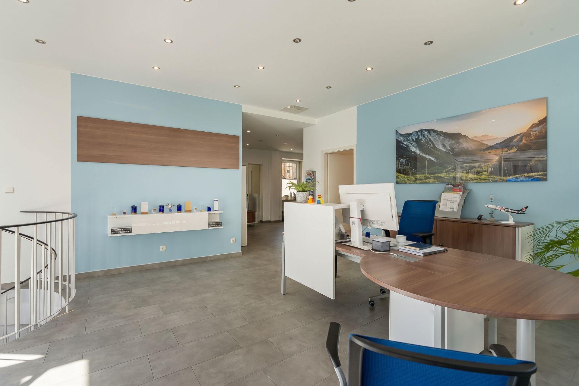 Modernes Zimmer mit Schreibtisch, Stühlen, blau gestrichener Wand und großem Landschaftsbild.