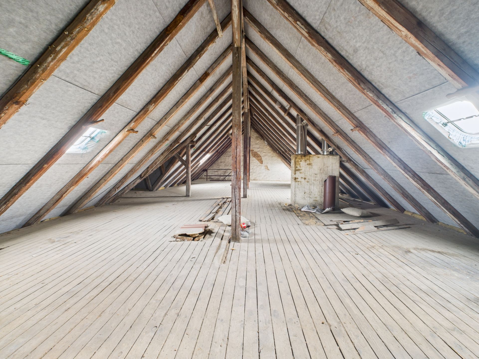 Großer, leerer Dachboden mit Holzfußboden und sichtbaren Balken.