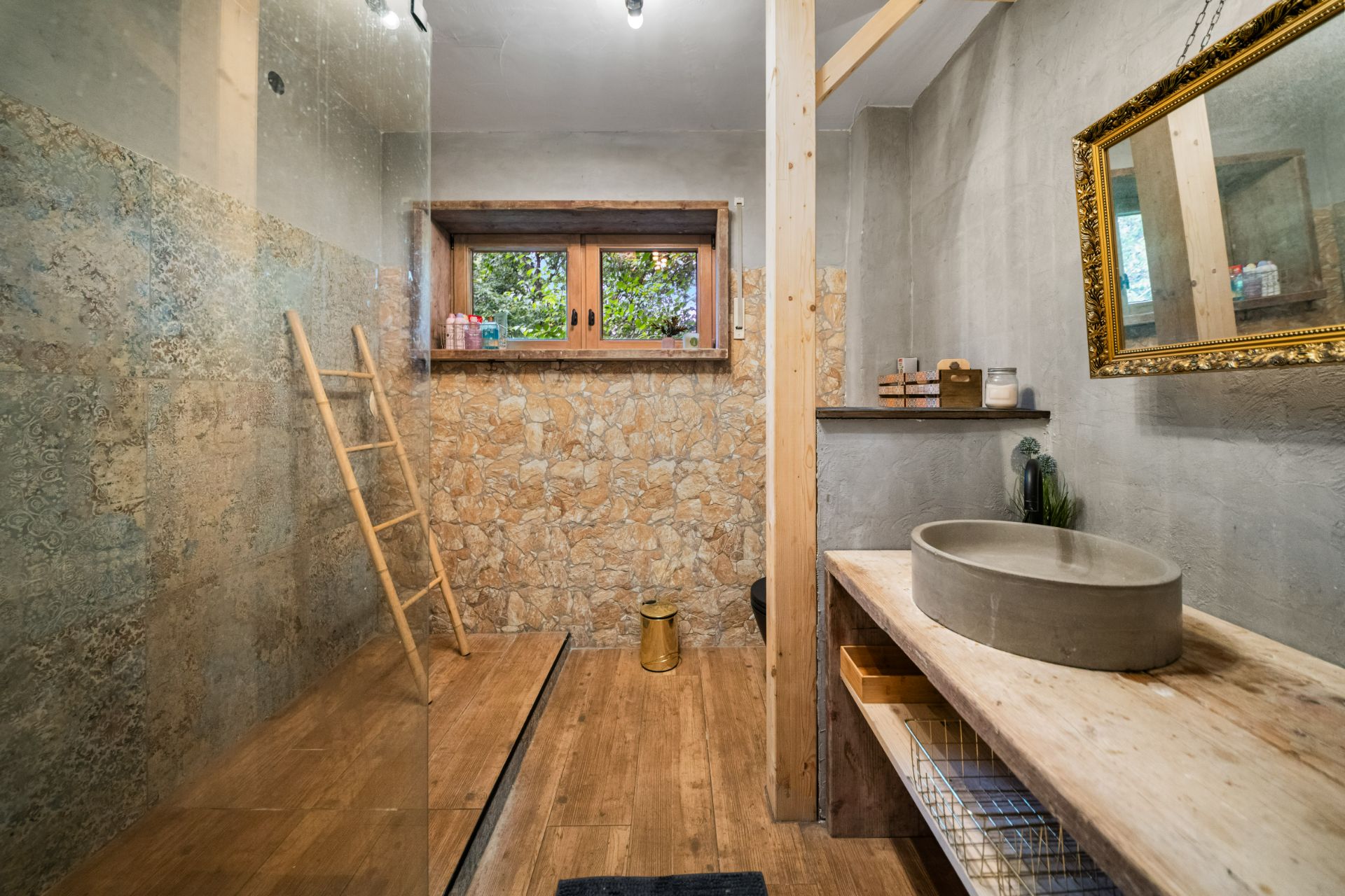 Rustikales Badezimmer mit Holzboden, Natursteinwand, runder Waschschüssel und bodengleicher Dusche.