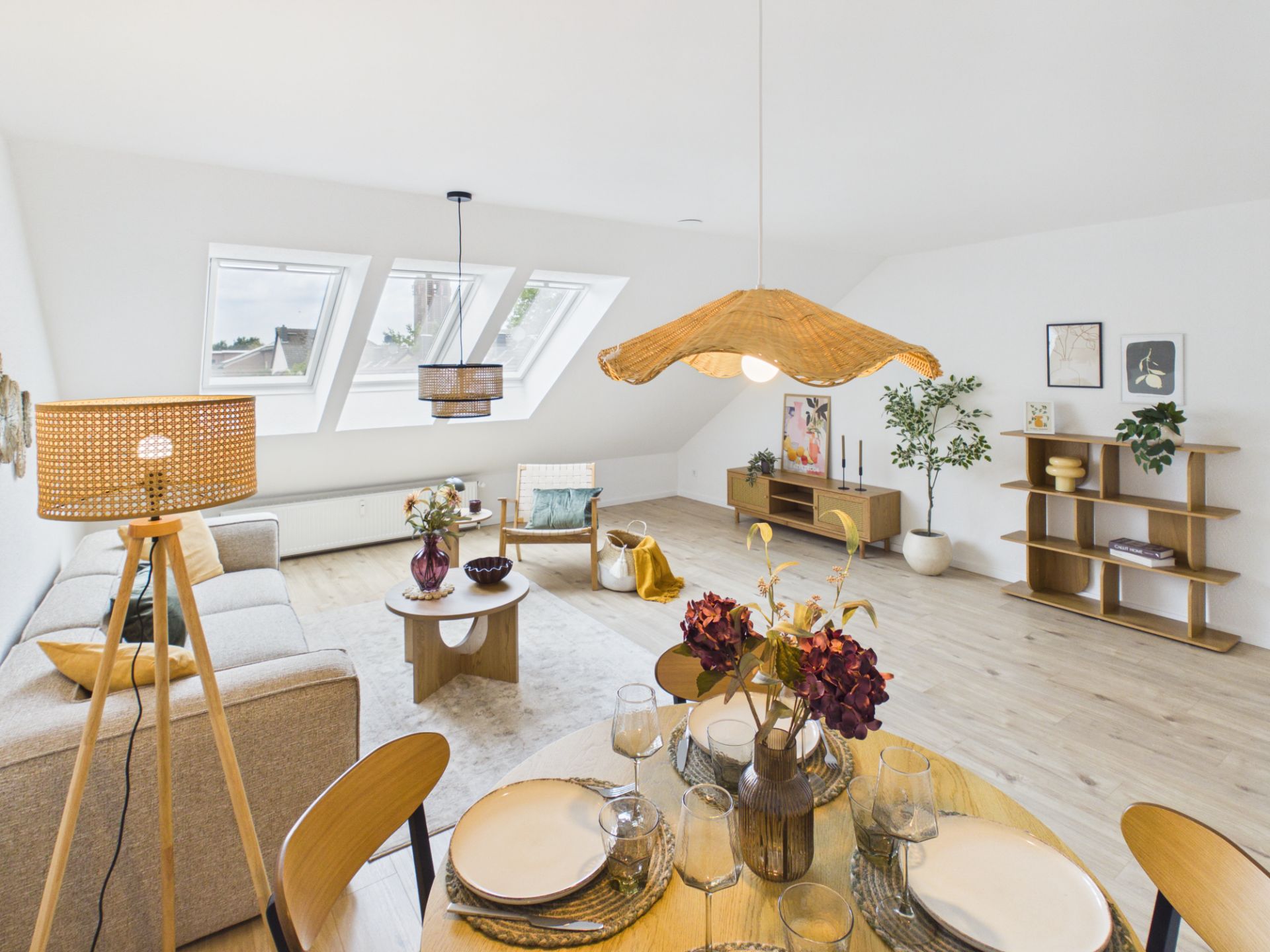 Modernes, helles Wohnzimmer mit Essbereich, Sofa, Regalen, Dekoration und großen Fenstern.