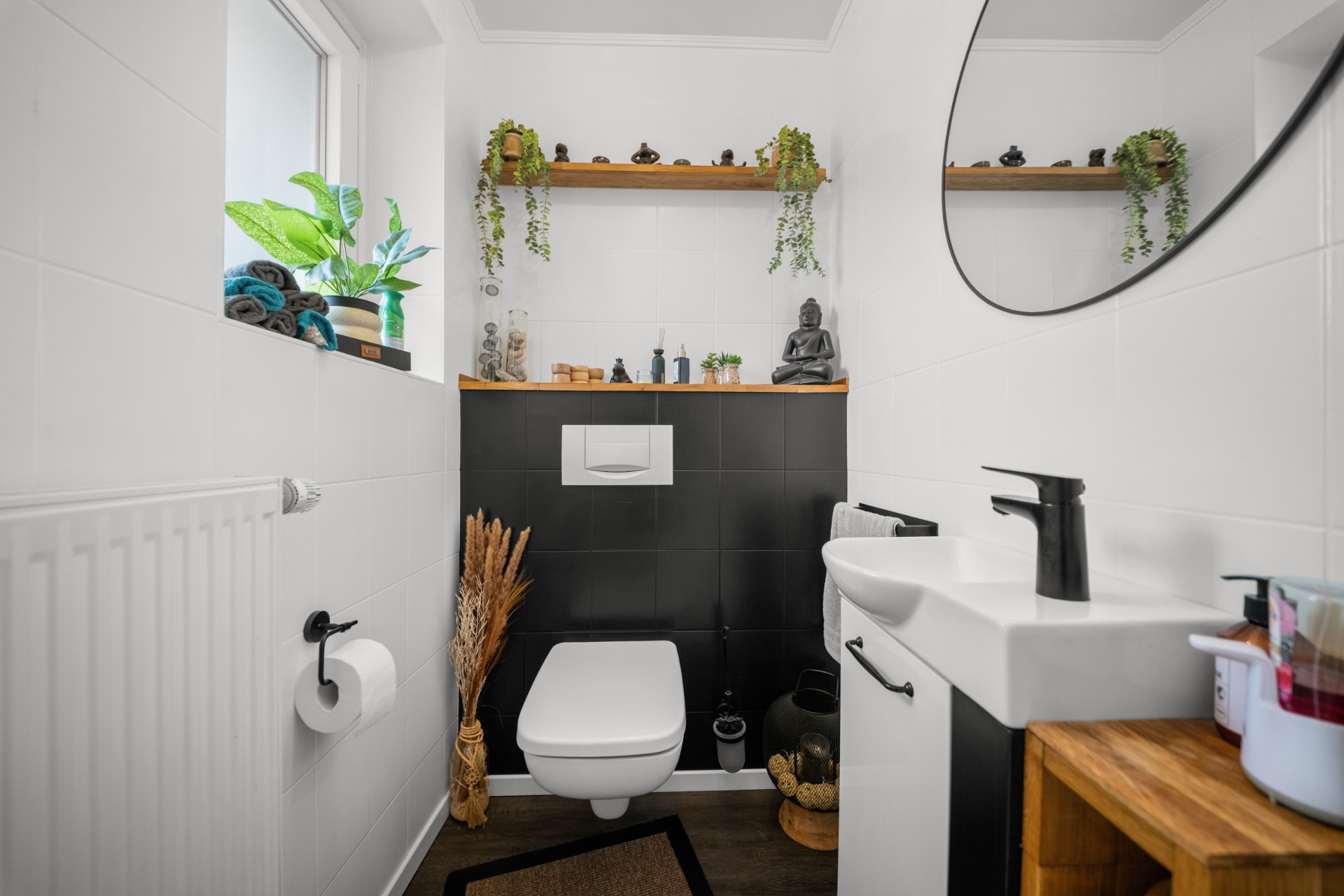 Modernes kleines Badezimmer mit Hänge-WC, kleinem Waschbecken, Pflanzen und dekorativen Regalbrettern an der Wand.