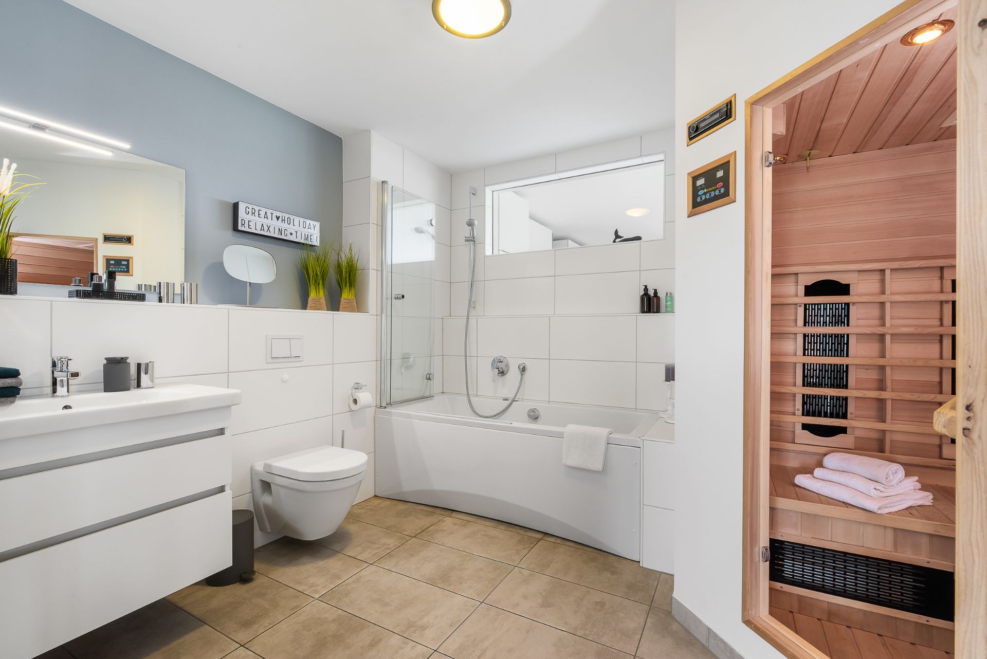 Modernes Bad mit Badewanne, Waschbecken, Toilette und einer Sauna mit Handtüchern.