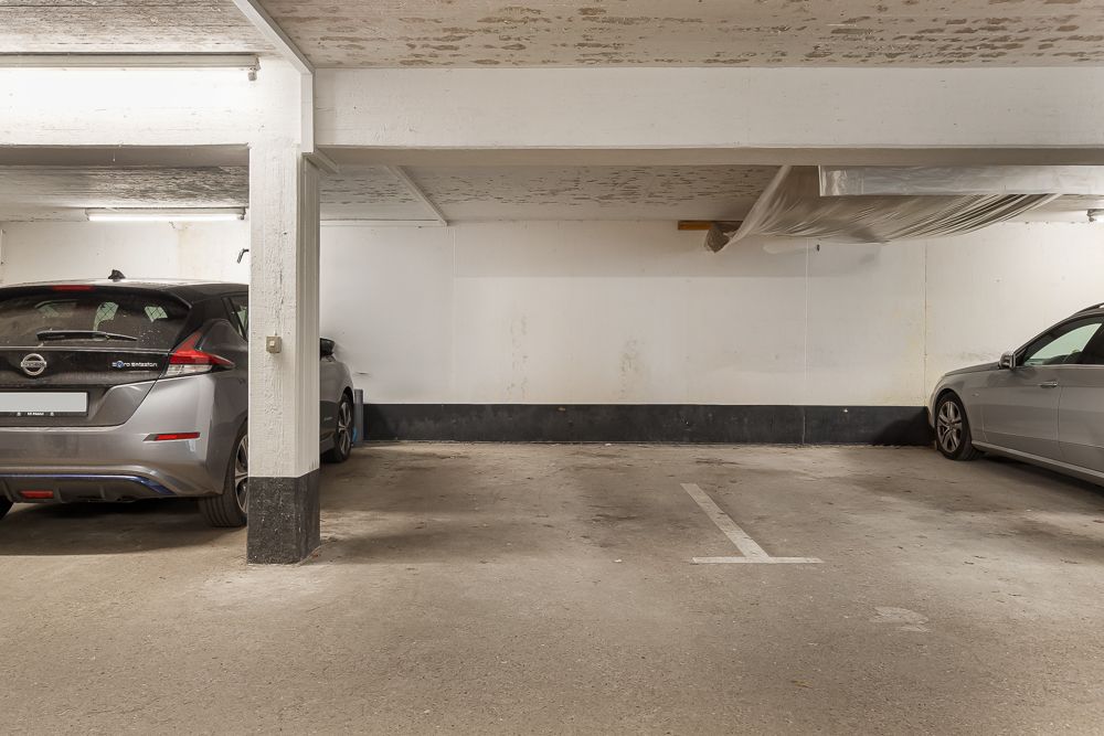 Tiefgaragenstellplätze mit zwei parkenden Autos und sichtbaren weißen Wänden.