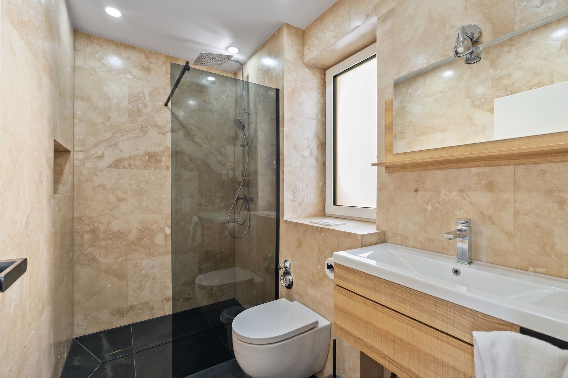 Modernes Bad mit begehbarer Dusche, WC, großem Spiegel und Holzmöbeln.