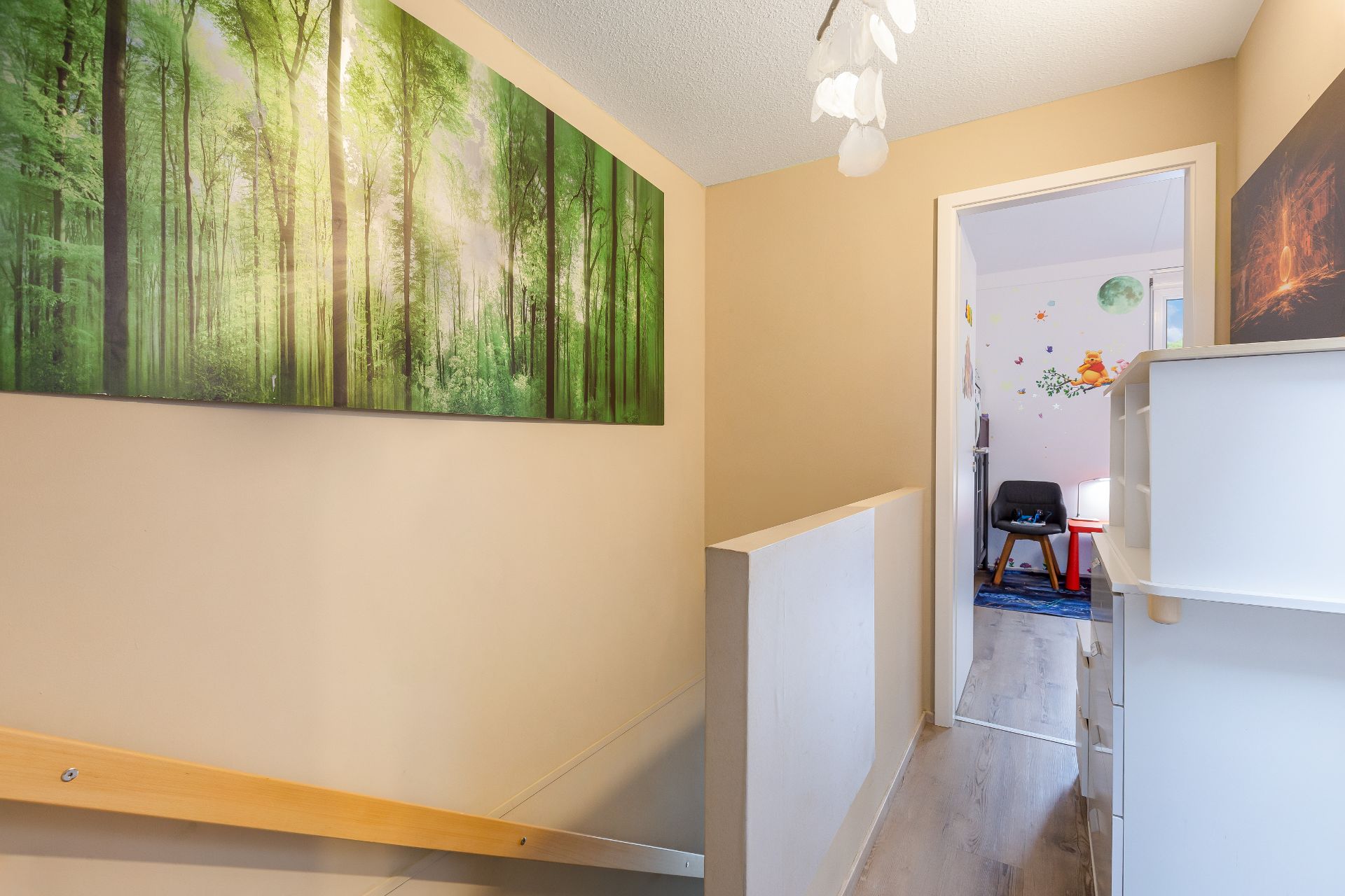 Flur mit Waldbild an der Wand, Blick in ein Kinderzimmer mit Wandaufklebern.