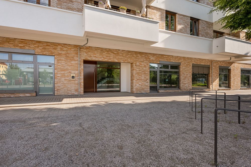 Moderne Wohnhausfassade mit großen Fenstern und Balkonen, davor Fahrradständer.