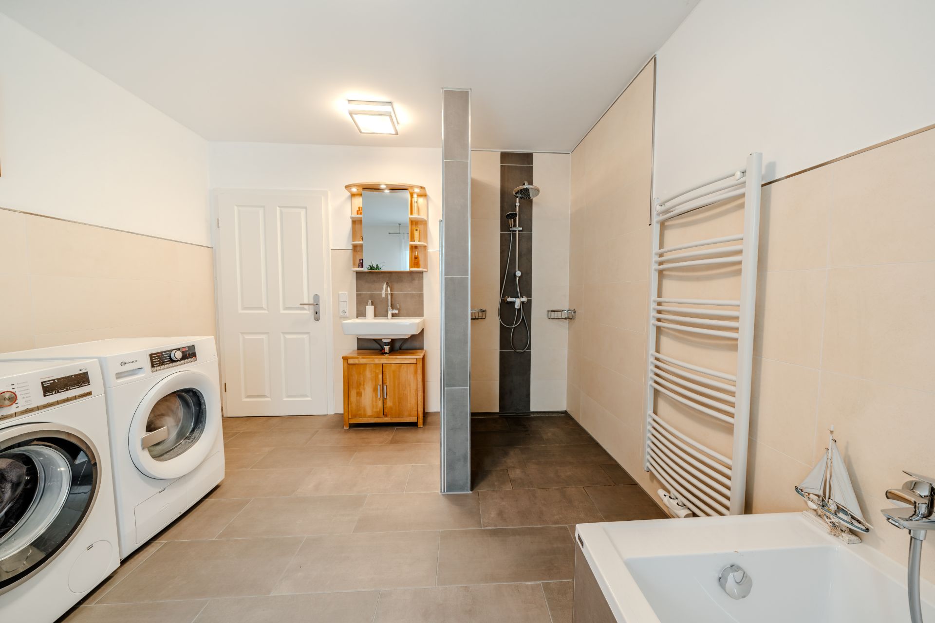 Modernes Badezimmer mit Dusche, Badewanne, Waschmaschine und Trockner.