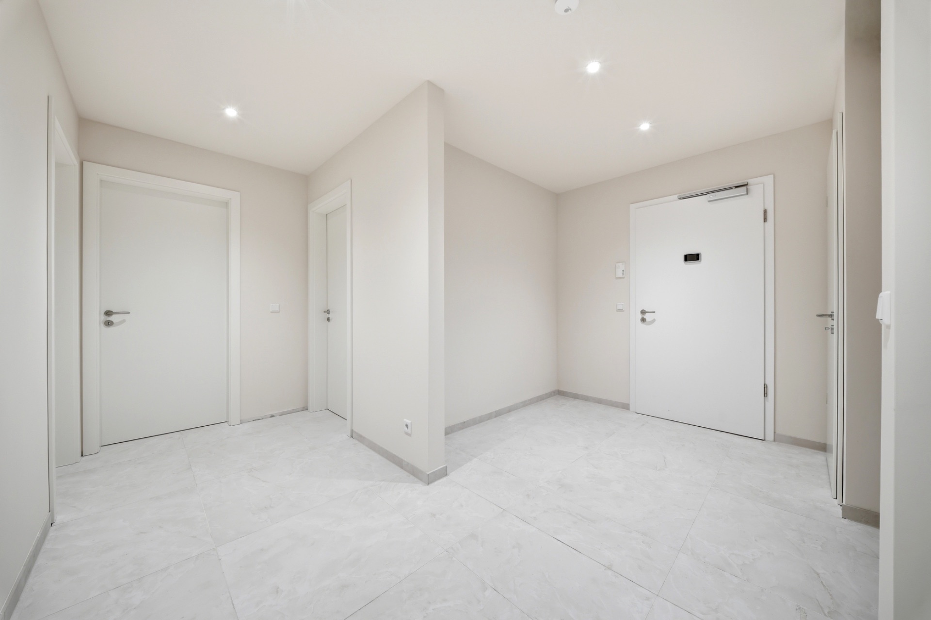 Heller Flur mit weißen Türen und hellen Fliesenboden in einer Wohnung.