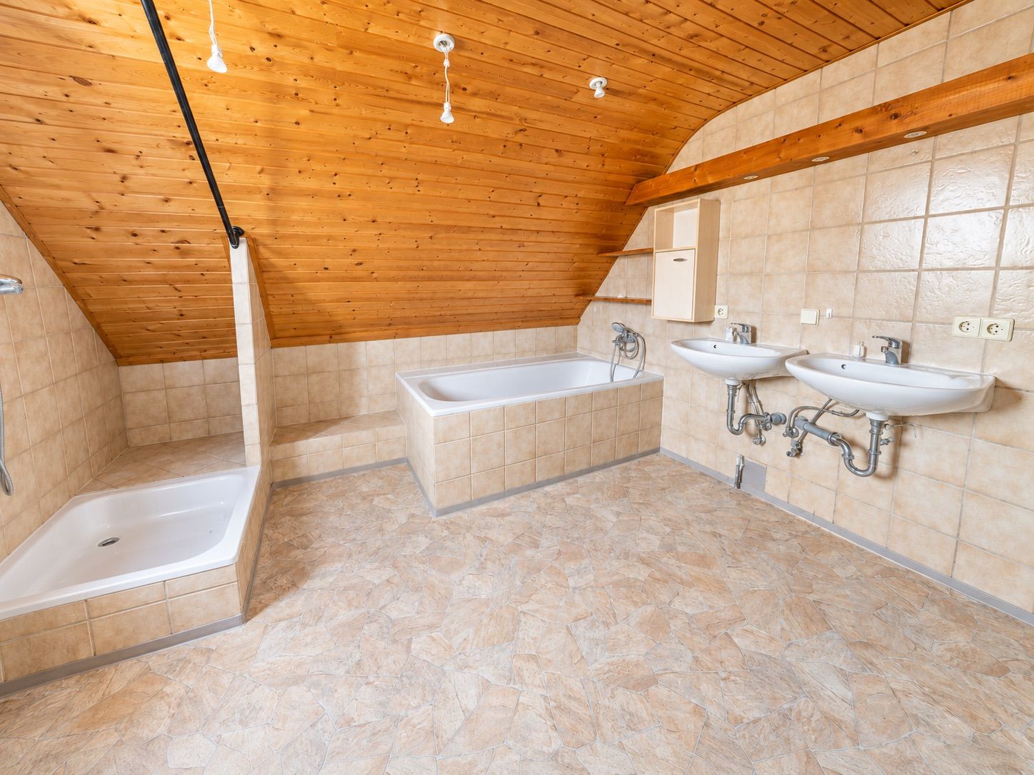 Helles Badezimmer mit Dachschräge, Dusche, Badewanne und zwei Waschbecken.