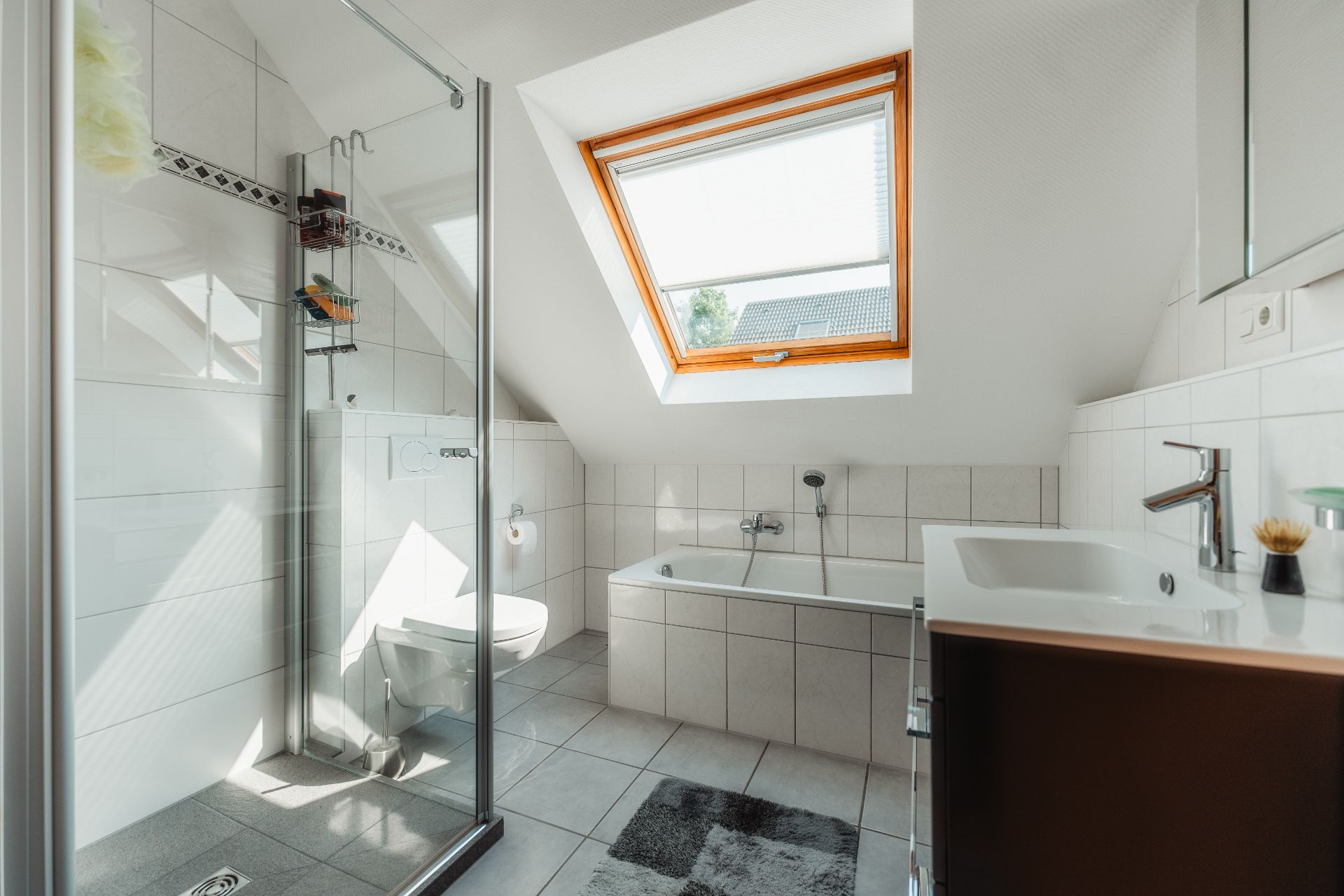 Modernes Badezimmer mit Dusche, Badewanne, Waschbecken und großem Dachfenster.